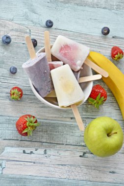 Bir ferahlık olarak yaz için mükemmel bir ahşap arka planda çilek, yaban mersini, elma ve muz ile ev yapımı dondurma