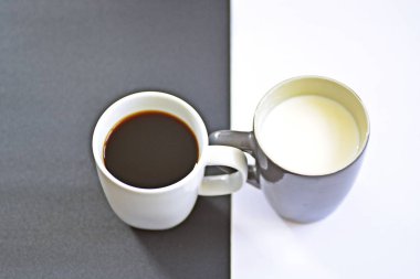 Yarım siyah ve yarım beyaz arka plan önünde iki bardak, bir fincan kahve içerir, diğer süt ve her ikisi de bir kontrast creat, kahve fincanları ile yin ve yang için kavram