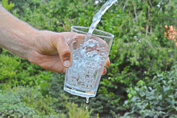Água Fresca Limpa Flui Copo Frente Fundo Verão Verde Segurado — Fotografia de Stock
