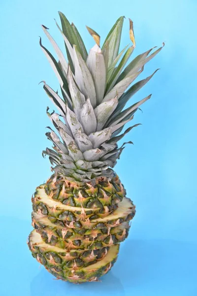 slices of a pineapple make up a whole pineapple in front of a solid background with space for text or objects