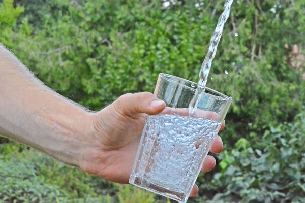 Čerstvá Čistá Voda Teče Skleničky Před Zelenou Sumí Drží Ruka — Stock fotografie