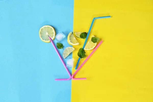 Concept for summer drink - Straws make up the glass in the lemons, limes, mint and ice floats against a colorful background - Abstract illustration of a summery refreshmentwith space for text