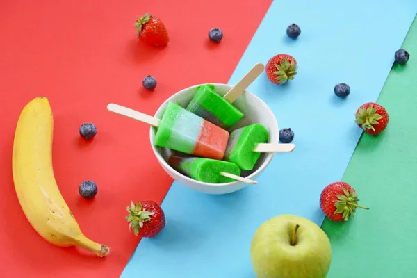 Homemade popsicle with strawberries, blueberries, apple and banana on a wooden background perfect for the summer as a refreshment