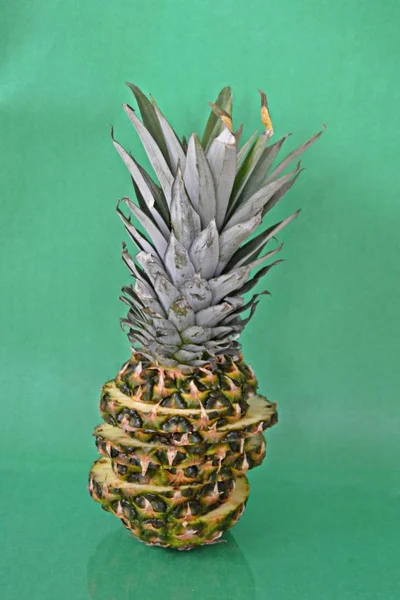 slices of a pineapple make up a whole pineapple in front of a solid background with space for text or objects