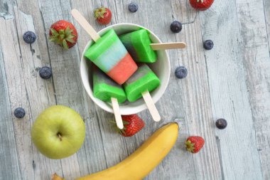 Bir ferahlık olarak yaz için mükemmel bir ahşap arka planda çilek, yaban mersini, elma ve muz ile ev yapımı dondurma 