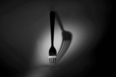 Işık kaynağı farklı yerleşim tarafından gölge deforme gösterimi ile beyaz bir arka plan üzerinde bir çatal gölge ile Kavram