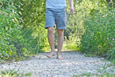 Ayaklarda yakın çekim - ormanda çakıl bir yol boyunca yürür ve yazlık sıcaklıklarda doğada rahatlatır