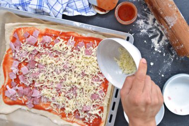 Yakın çekim-Man, jambon, salam ve peynir pişirme levha yanında malzemeler ile pizza hamur dolu bir pizza dolduruyor 