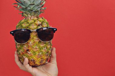 elinde güneş gözlüğü ile bir ananas tutarak