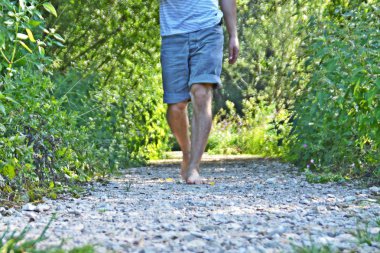 Ayaklarda yakın çekim - ormanda çakıl bir yol boyunca yürür ve yazlık sıcaklıklarda doğada rahatlatır
