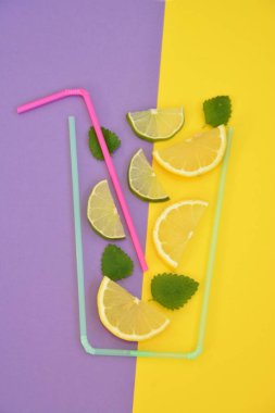 Yaratıcı düzeni çilek limonata malzemeler - limon, narenciye, buz renkli arka plan üzerinde kokteyl pipetleri ile yapılan cam düşen. Yaz içkileri. Minimal gıda konsepti. Seçici odaklama.