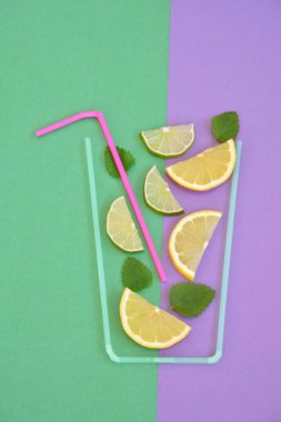 Yaratıcı düzeni çilek limonata malzemeler - limon, narenciye, buz renkli arka plan üzerinde kokteyl pipetleri ile yapılan cam düşen. Yaz içkileri. Minimal gıda konsepti. Seçici odaklama.