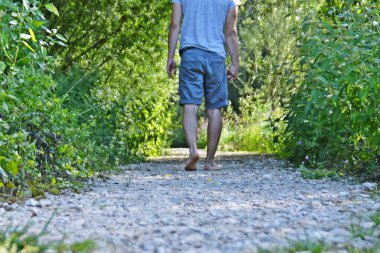 Ayaklarda yakın çekim - ormanda çakıl bir yol boyunca yürür ve yazlık sıcaklıklarda doğada rahatlatır