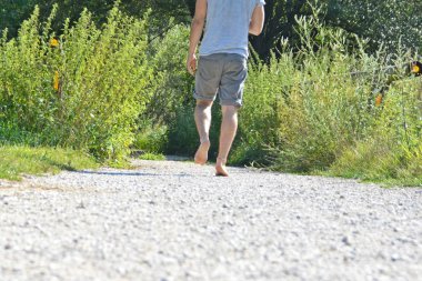 Ayaklarda yakın çekim - ormanda çakıl bir yol boyunca yürür ve yazlık sıcaklıklarda doğada rahatlatır