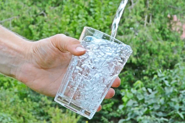 Água Fresca Limpa Flui Copo Frente Fundo Verão Verde Segurado — Fotografia de Stock