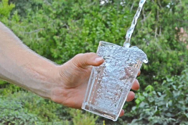 Água Fresca Limpa Flui Copo Frente Fundo Verão Verde Segurado — Fotografia de Stock