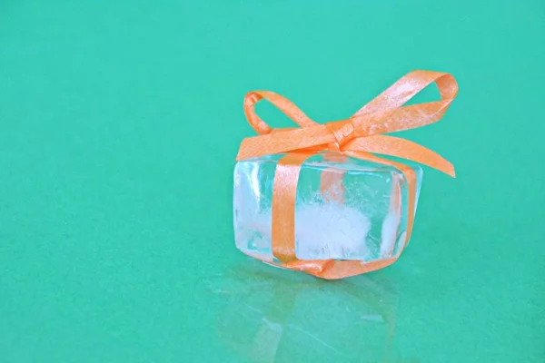 Ice cube with a bow in front of white background