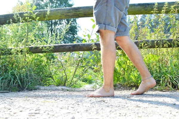 Close-up on the feet - walks across a pebble path in the woods and relaxes in the nature at summery temperatures