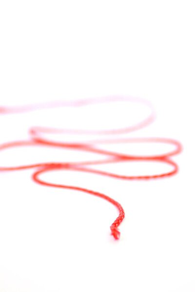 Немецкая фраза "нить рассказа" абстрактно изображена как картинка с красной нитью перед белым фоном - представляет внутреннюю последовательность истории
