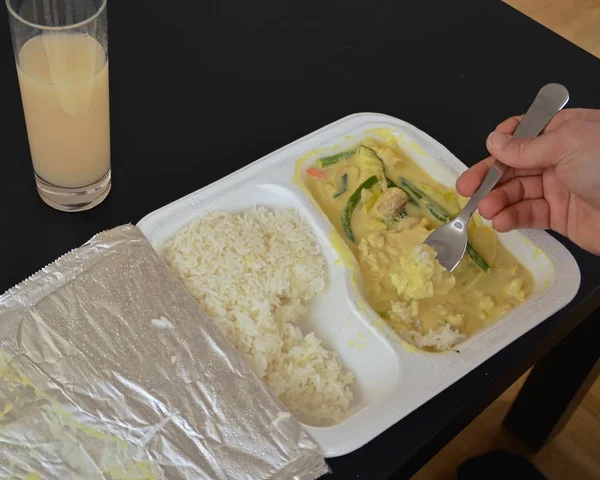 Close-up: eat yellow curry with rice from a styrofoam box with chopsticks