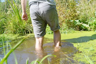 Ayakları üzerinde yakın çekim - Adam bitkiler büyüyor küçük bir nehir ile yaz aylarında çalışıyor 
