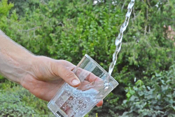 Čerstvá Čistá Voda Teče Skleničky Před Zelenou Sumí Drží Ruka — Stock fotografie