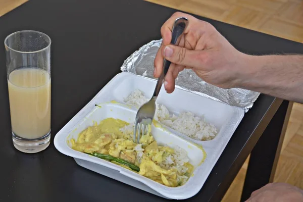 Close-up: eat yellow curry with rice from a styrofoam box with chopsticks