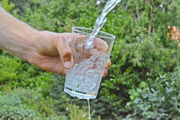 Свіжа Чиста Вода Тече Склянці Перед Зеленим Літнім Тлом Тримається — стокове фото