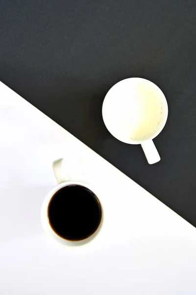 Две Чашки Фоне Получёрного Полубелого Фона Одна Чашка Содержит Кофе — стоковое фото