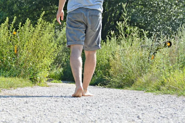 Close-up on the feet - walks across a pebble path in the woods and relaxes in the nature at summery temperatures