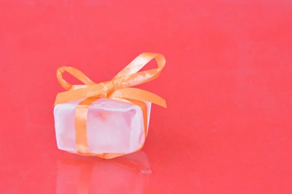 Ice cube with a bow in front of white background