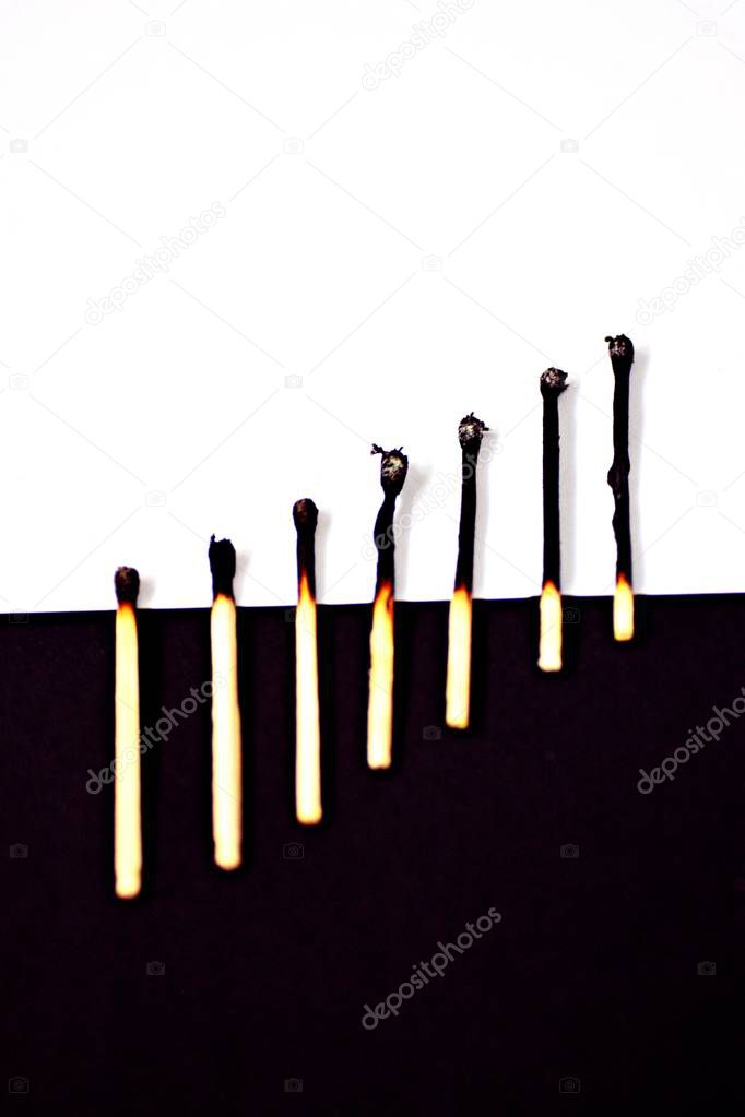 Course of new to burnt match in front of white and black background - concept with strong contrasts 