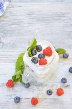 Kahvaltıda yoğurt, yaban mersini ve ahududu ile yulaf ezmesi ve müsli - Sağlıklı yemek - Kahvaltı yiyen bir adamın yakın çekim 