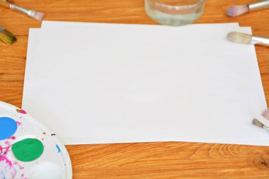 Bir renk paleti ve birçok fırça lar yanı sıra ahşap bir arka plan üzerinde fırça su renkleri ile bir kağıt levha