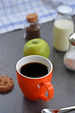Elma, süt, şeker ve bisküvi ile bir masada bir portakal fincan Kahve 