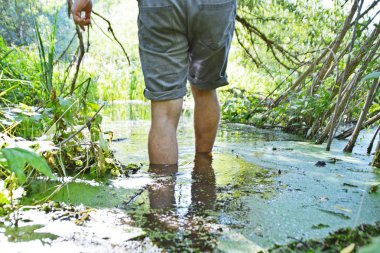 Ayakları üzerinde yakın çekim - Adam bitkiler büyüyor küçük bir nehir ile yaz aylarında çalışıyor 