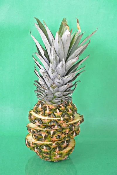 slices of a pineapple make up a whole pineapple in front of a solid background with space for text or objects