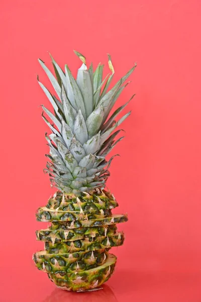 slices of a pineapple make up a whole pineapple in front of a solid background with space for text or objects