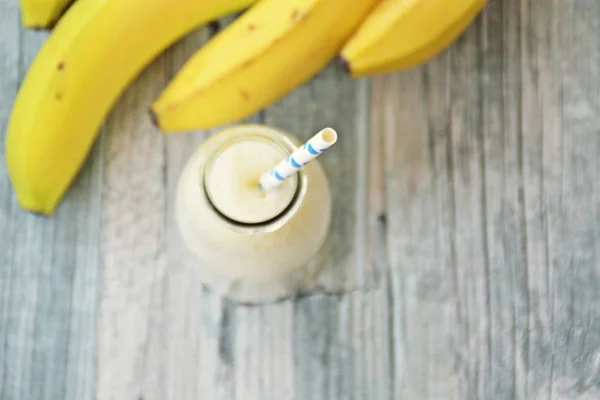 banana milkshake with straw on wooden background