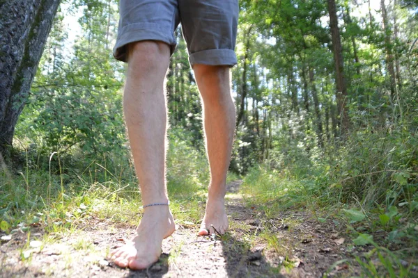 Close-up on the feet - walks across a pebble path in the woods and relaxes in the nature at summery temperatures