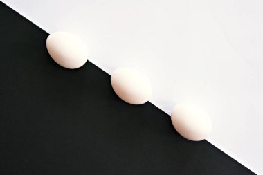 Beyaz bardak ile tavuk yumurtası beyaz yumurta ve küçük gölge ile arka plan olarak güçlü bir kontrast ile yarım beyaz ve yarım siyah arka plan önünde yalan