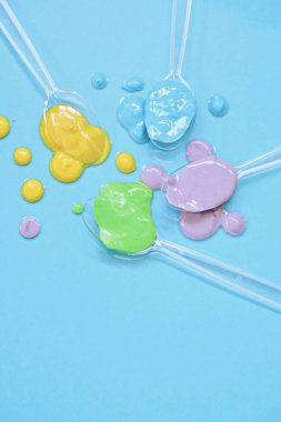 Düz bir arka planda boya farklı damla ile şeffaf kaşıklar-metin alanı ile arka plan olarak renk ile plastik kaşık 
