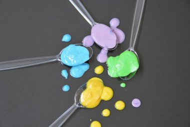 Düz bir arka planda boya farklı damla ile şeffaf kaşıklar-metin alanı ile arka plan olarak renk ile plastik kaşık 