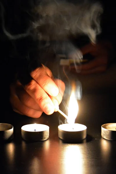 light up a row of candles in the dark with a match - light up candle in a cold evening with focus on the candle and low lightning