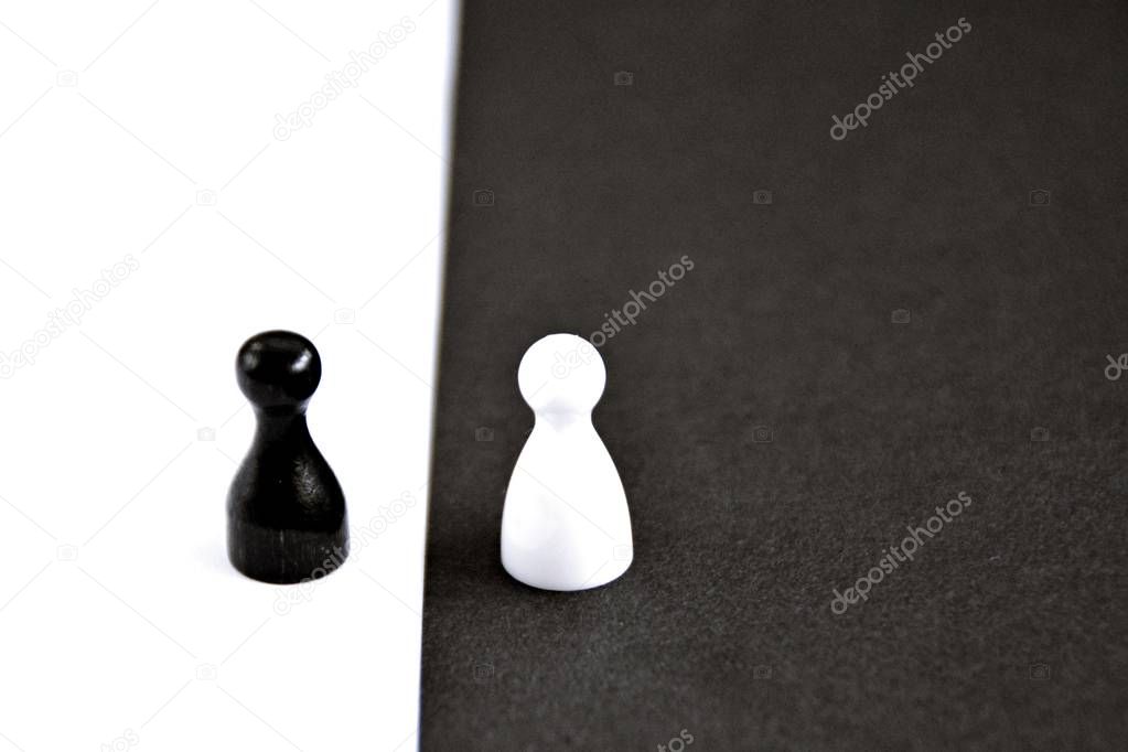 A black pawn stands in front of a white background and vice versa - concept with strong contrasts as a symbol of differences and equality, as well as ying and yang