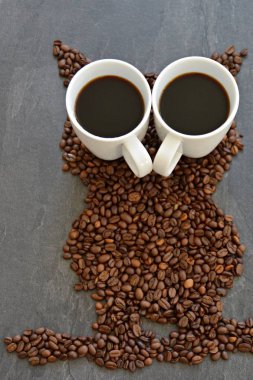 Siyah bir arka planda kahve çekirdekleri bir baykuş silüeti ve kahve ve gece baykuşlar ile gözleri-kavramı iki fincan kahvenin formu