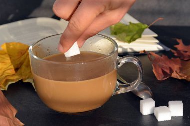 Bir cam fincan içine bir sonbahar ayarı kahve dökün-bir cam fincan kuru ve renkli sonbahar yaprakları ve arka planda bir kitap yanında standig ve birisi içine kahve dökme olduğunu