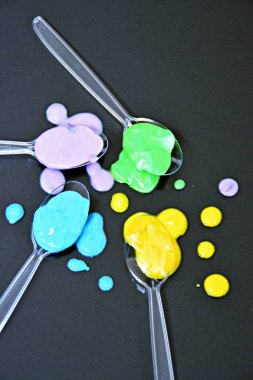 Düz bir arka planda boya farklı damla ile şeffaf kaşıklar-metin alanı ile arka plan olarak renk ile plastik kaşık 