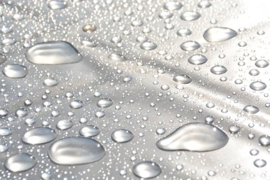 Su Damlaları bir yağmurdan sonra plastik bir sargı üzerinde toplamak ve yağmurdan sonra parlayan güneşi yansıtır - ışık, yağmur damlaları ve güneş ile doğal bir oyun