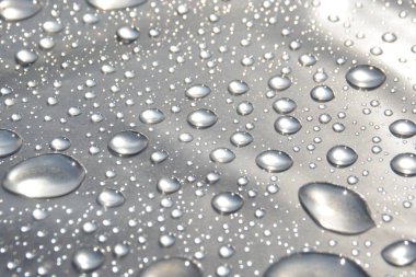 Su Damlaları bir yağmurdan sonra plastik bir sargı üzerinde toplamak ve yağmurdan sonra parlayan güneşi yansıtır - ışık, yağmur damlaları ve güneş ile doğal bir oyun